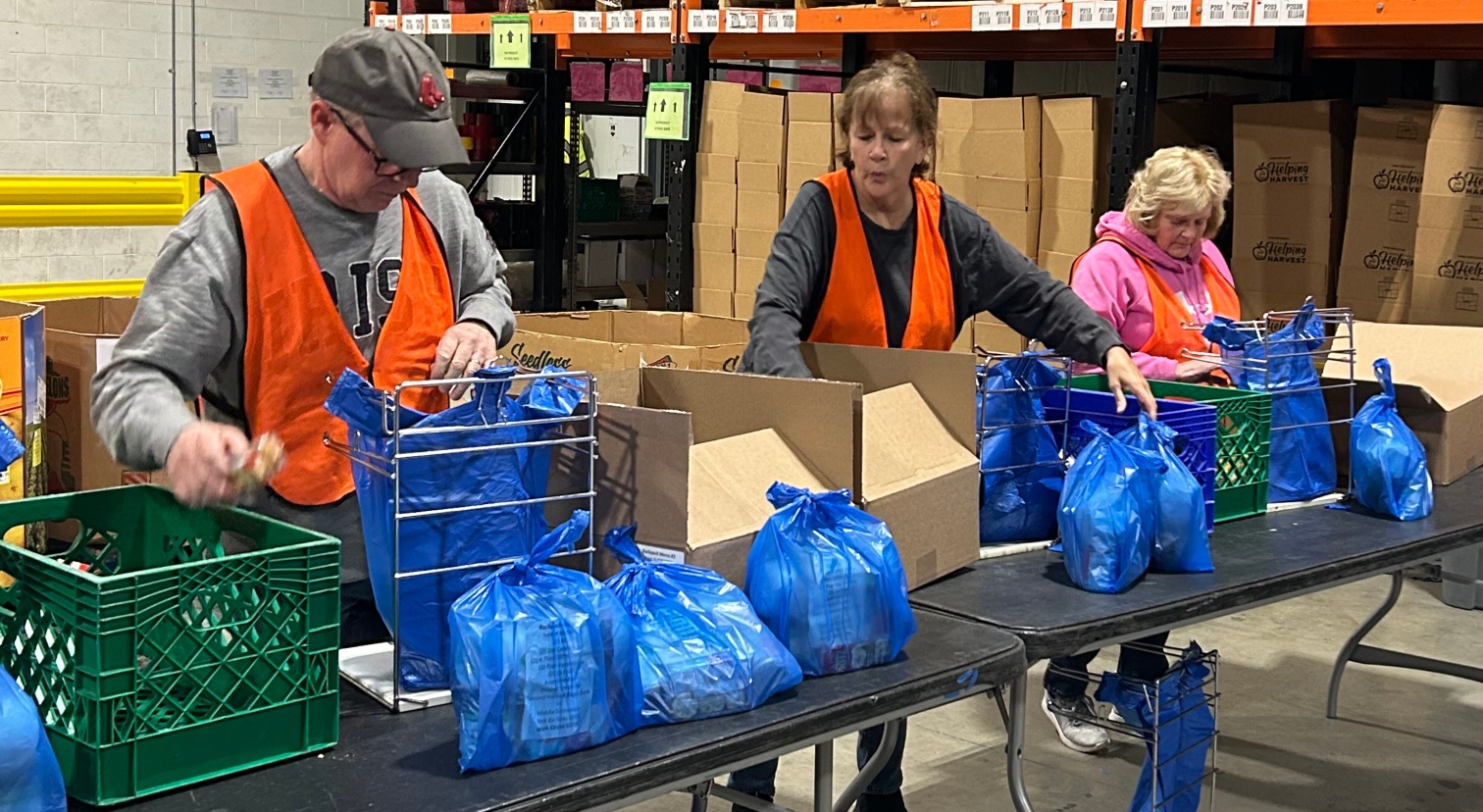 Three adults load bags with healthy non-perishable items