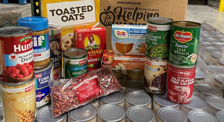 A variety of canned and boxed food items sit in front of a cardboard box