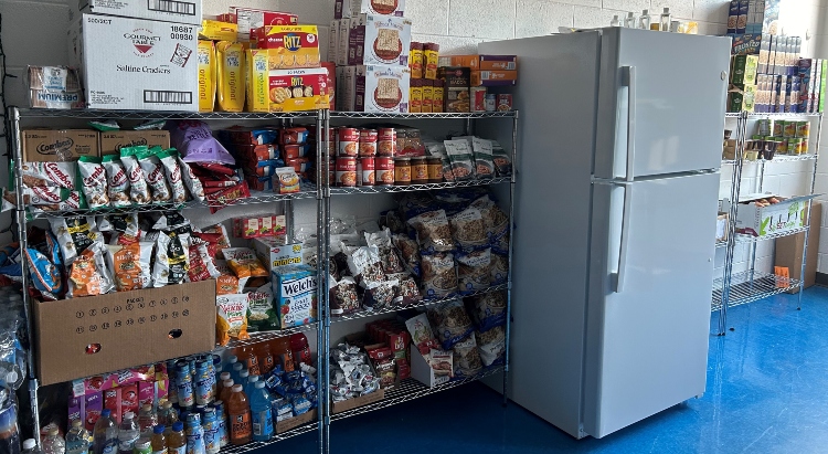 Shelves stocked with food beside a refrigerator in a school